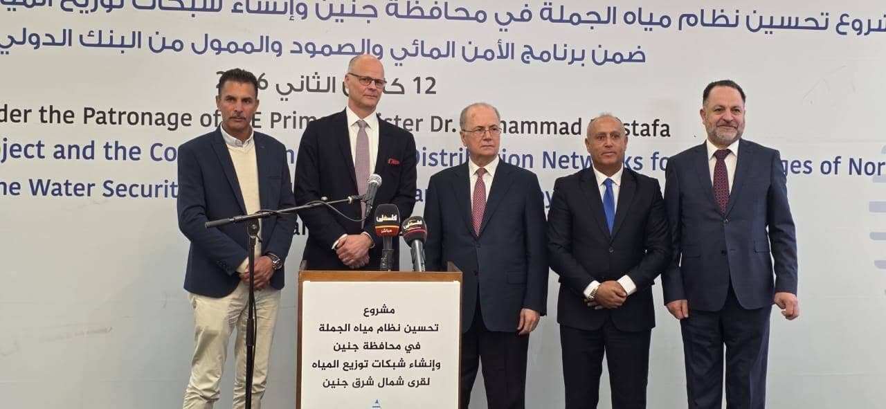 صورة جماعية للمشاركين خلال فعالية أمام منصة للمتحدثين