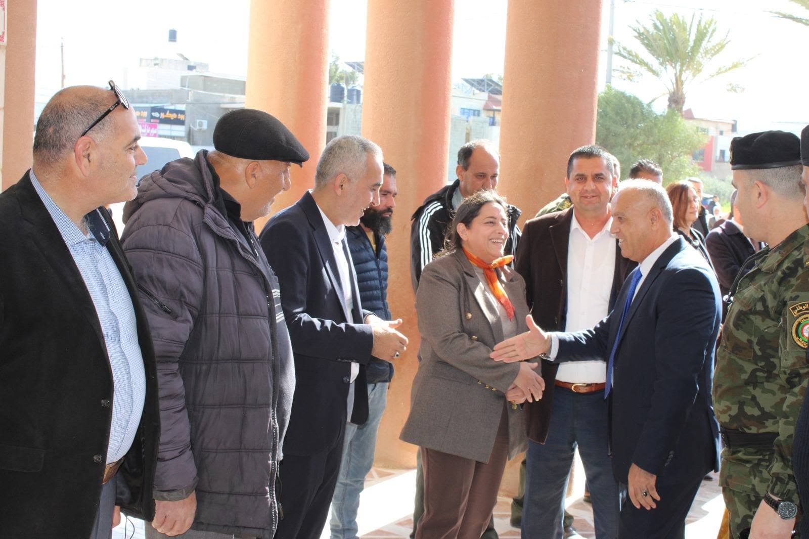 مجموعة من المشاركين يتبادلون التحية عند مدخل مبنى